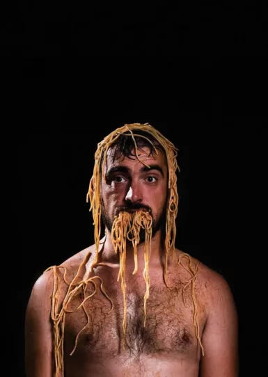 Homme avec assiette de spaghettis renversés sur la tête