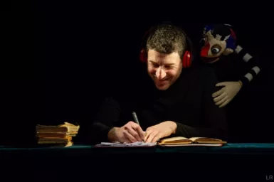 Homme écrivant avec marionnette sur l'épaule