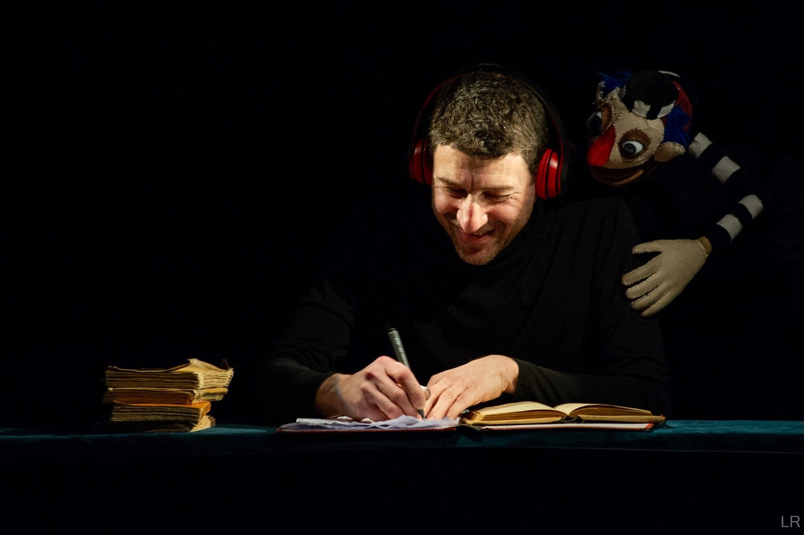 Homme écrivant avec marionnette sur l'épaule